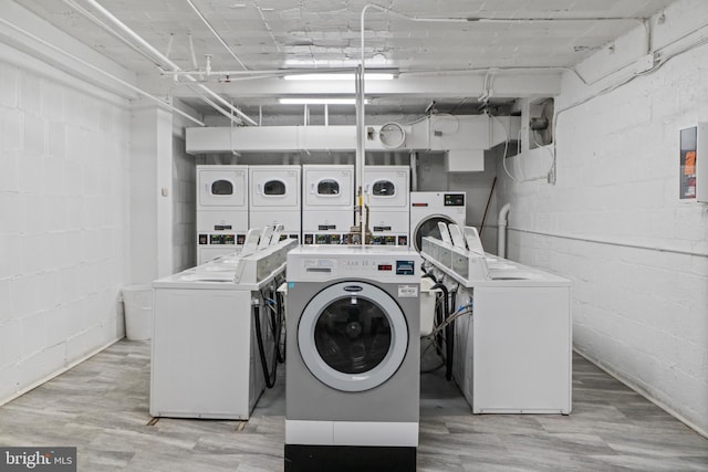 laundry room with washing machine and clothes dryer, stacked washer / drying machine, and light hardwood / wood-style floors