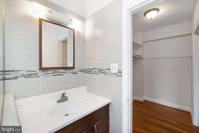 bathroom featuring vanity, wood-type flooring, and tile walls