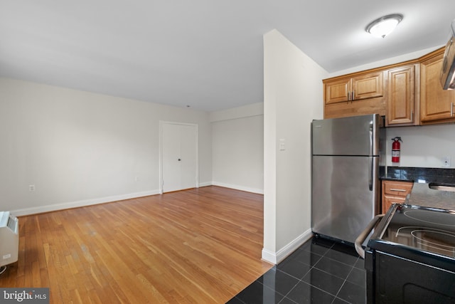 kitchen with black range with electric stovetop, dark wood-type flooring, and stainless steel refrigerator