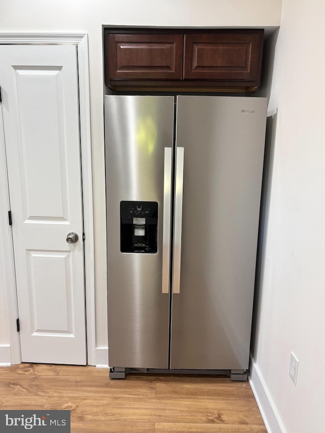 details with stainless steel refrigerator with ice dispenser, dark brown cabinets, and light wood-type flooring