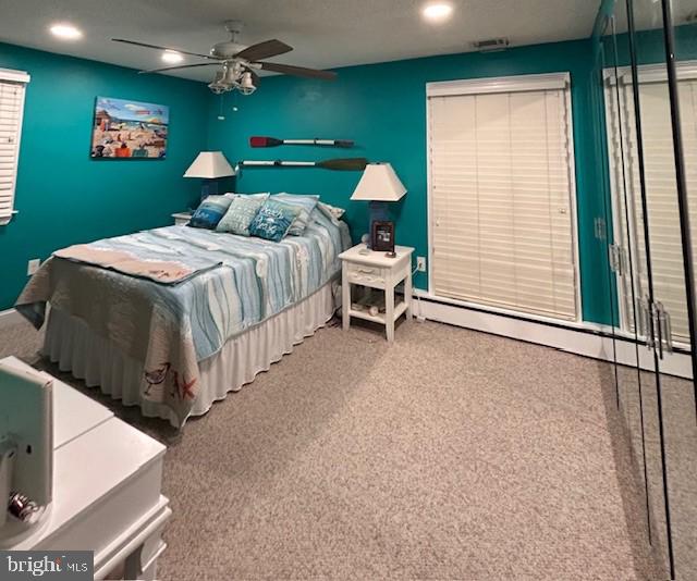 bedroom featuring a baseboard heating unit, ceiling fan, and carpet flooring