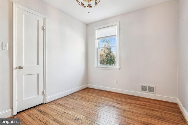 spare room featuring light wood-style floors, visible vents, and baseboards