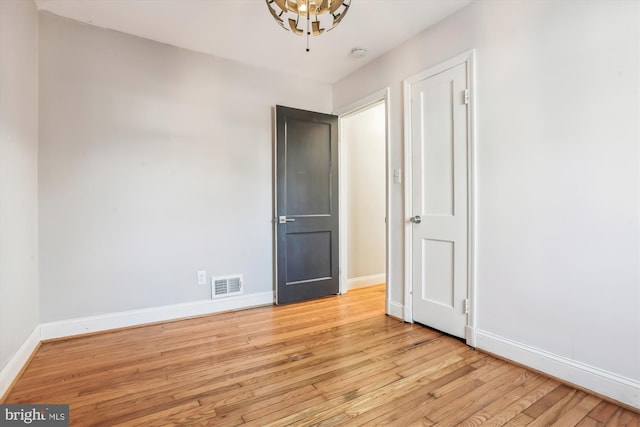 empty room featuring visible vents, baseboards, and wood finished floors