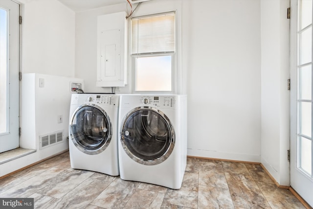 washroom featuring washing machine and clothes dryer, visible vents, laundry area, electric panel, and baseboards