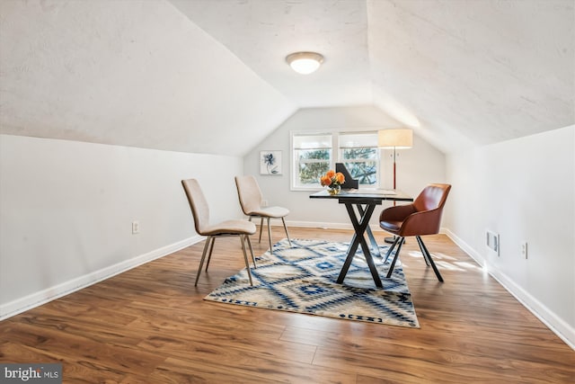 interior space featuring lofted ceiling, visible vents, baseboards, and wood finished floors