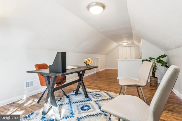 office space with lofted ceiling, baseboards, visible vents, and wood finished floors