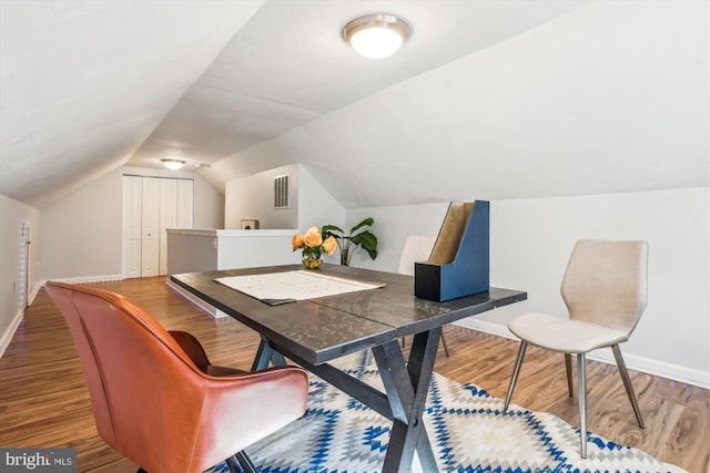 interior space featuring lofted ceiling, wood finished floors, and baseboards