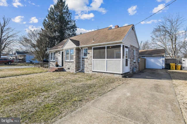 view of front of house featuring driveway, a shingled roof, stone siding, an outbuilding, and a front yard