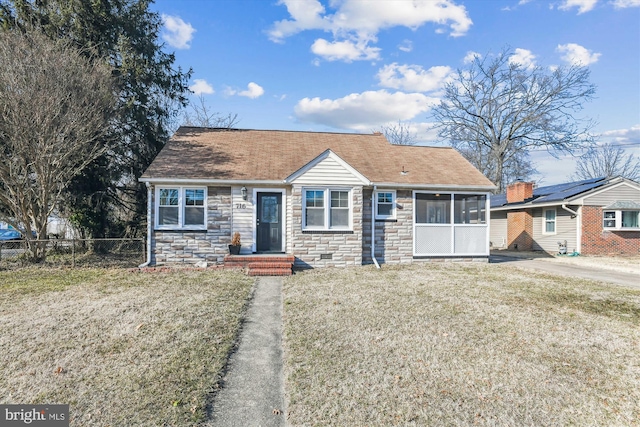 view of front of house featuring stone siding, a shingled roof, fence, and a front lawn