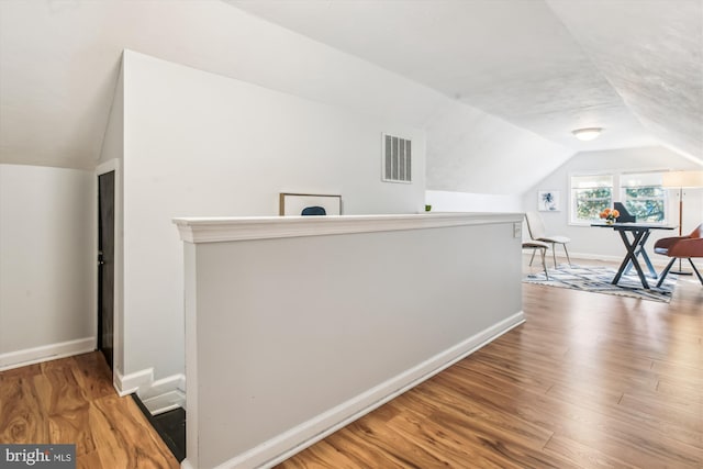 bonus room with lofted ceiling, wood finished floors, visible vents, and baseboards