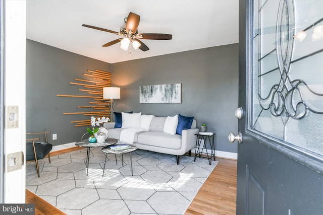 living room with a ceiling fan, baseboards, and wood finished floors