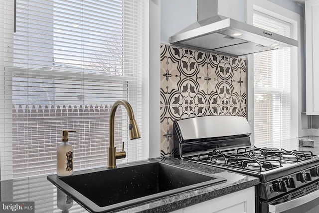 kitchen featuring white cabinetry, sink, plenty of natural light, wall chimney range hood, and black gas range