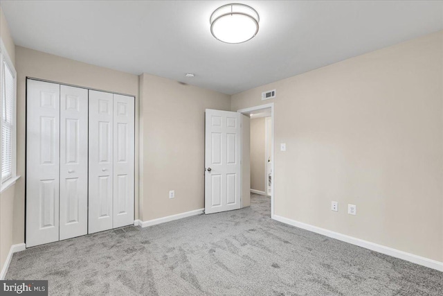 unfurnished bedroom with light colored carpet and a closet