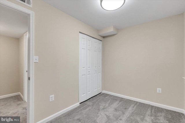 unfurnished bedroom with light carpet and a closet