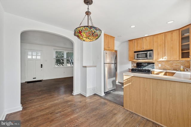 kitchen featuring stainless steel appliances, hanging light fixtures, dark wood-type flooring, and backsplash