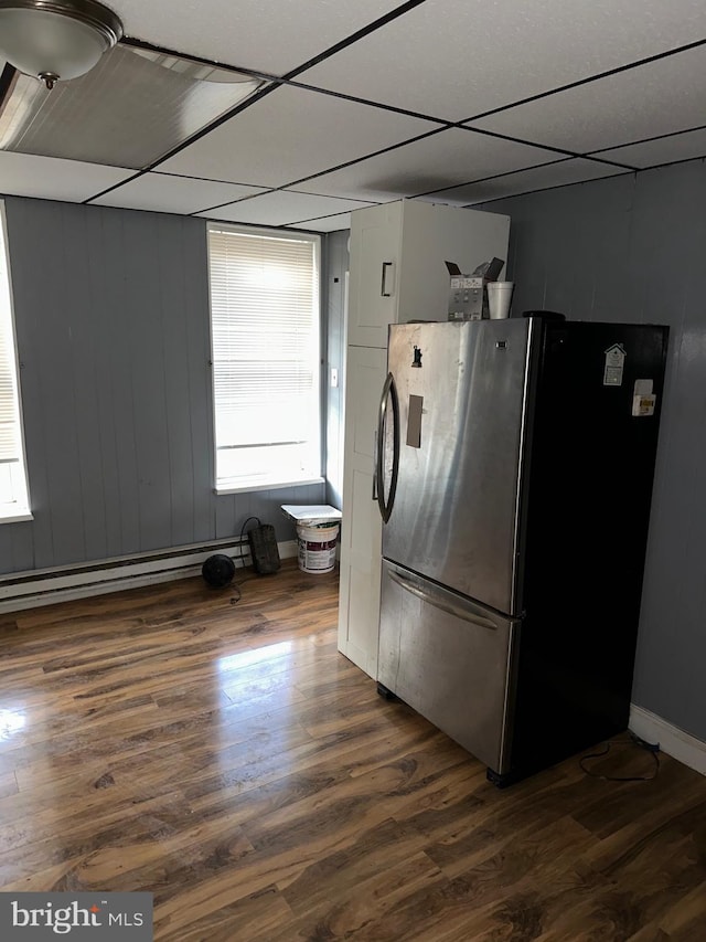 kitchen with a baseboard heating unit, dark wood-type flooring, stainless steel refrigerator, and a paneled ceiling