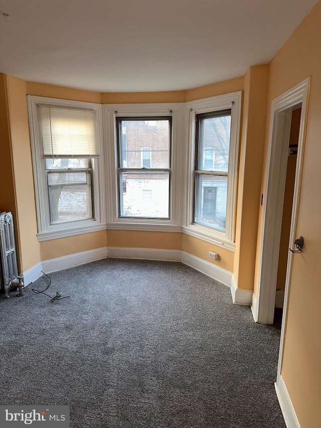 spare room with radiator heating unit and dark carpet