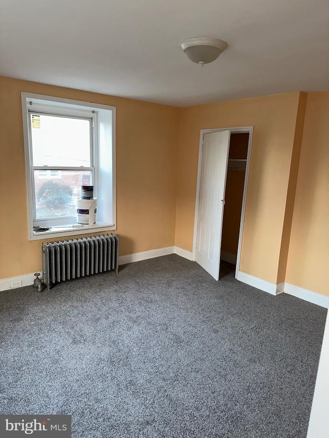 unfurnished bedroom with radiator heating unit and carpet