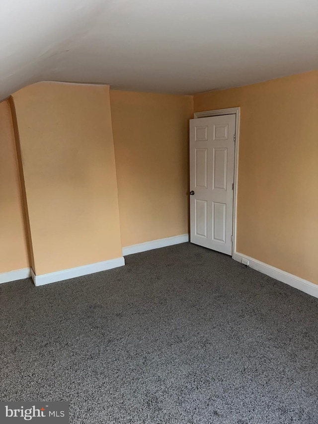 carpeted empty room featuring vaulted ceiling