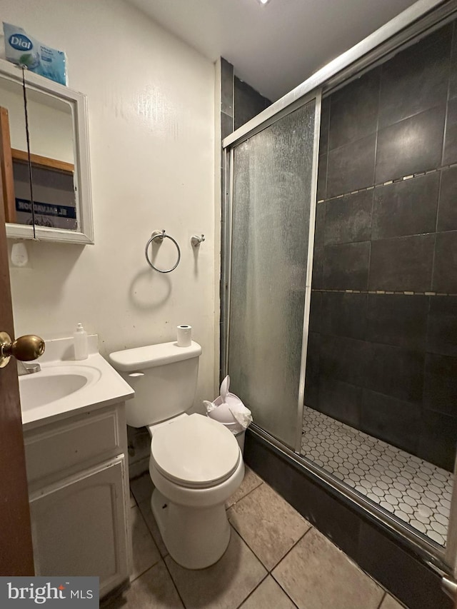 bathroom with vanity, toilet, a shower with shower door, and tile patterned flooring