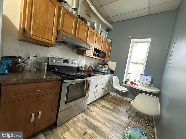 kitchen featuring tasteful backsplash, a drop ceiling, light hardwood / wood-style floors, and electric stove