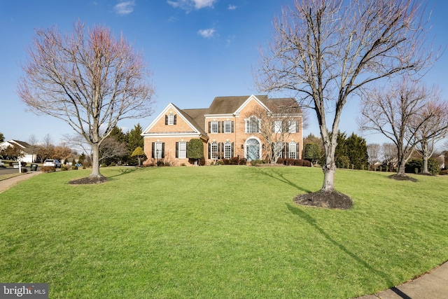 colonial inspired home featuring a front yard and brick siding