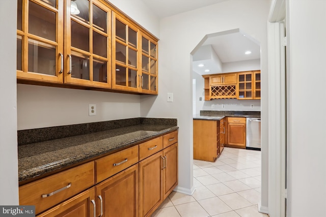 kitchen featuring dishwasher, light tile patterned floors, and dark stone countertops