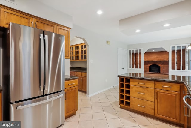 kitchen with dark stone countertops, stainless steel refrigerator, and light tile patterned floors