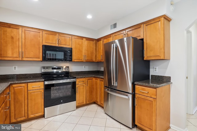 kitchen featuring light tile patterned flooring, appliances with stainless steel finishes, and dark stone counters