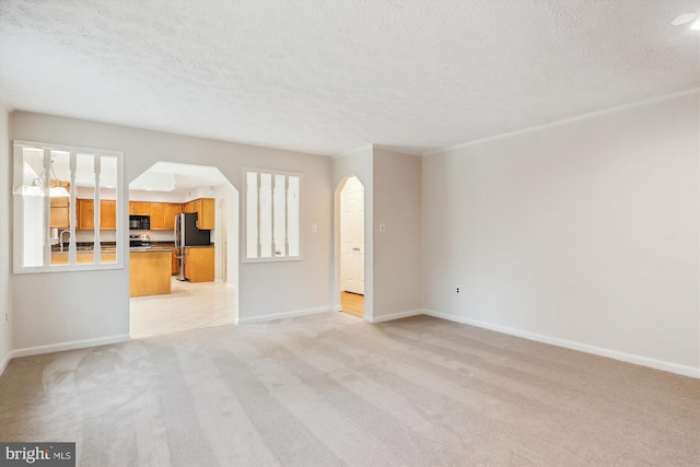 unfurnished living room with sink, light carpet, and a textured ceiling