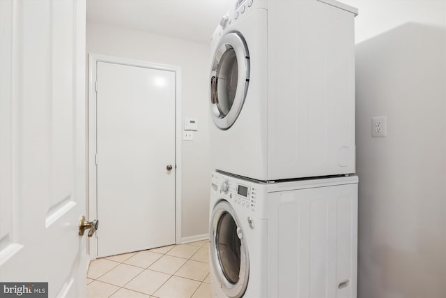 laundry room with light tile patterned flooring and stacked washer / dryer