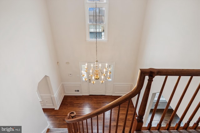 stairs featuring hardwood / wood-style flooring and an inviting chandelier