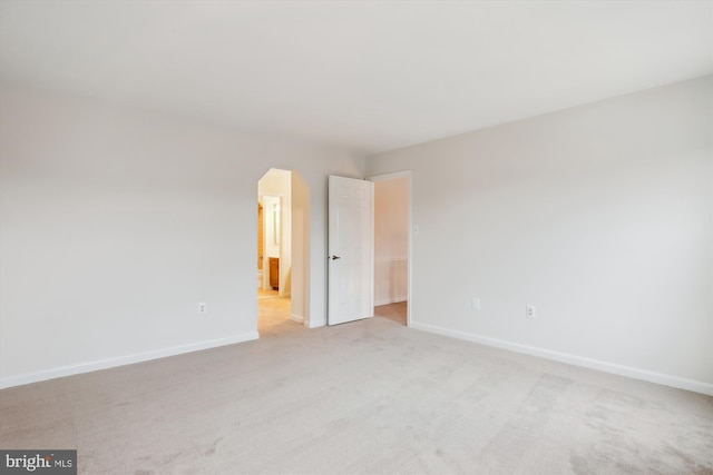 unfurnished bedroom featuring light colored carpet and ensuite bathroom