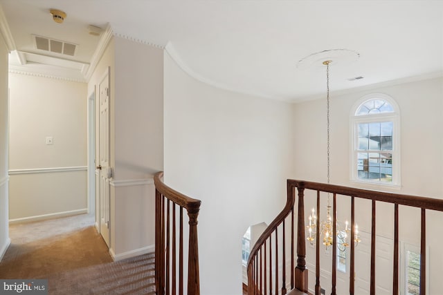 hall with ornamental molding, a chandelier, and light carpet