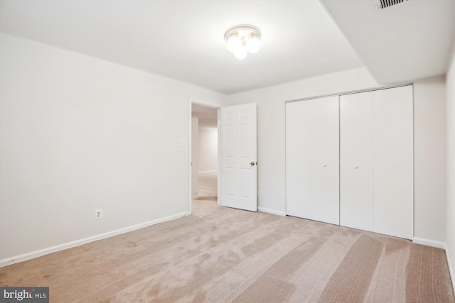 unfurnished bedroom featuring light colored carpet and a closet