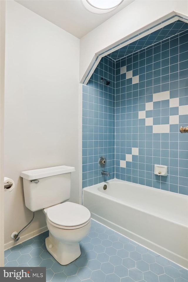 bathroom with tiled shower / bath combo, tile patterned floors, and toilet