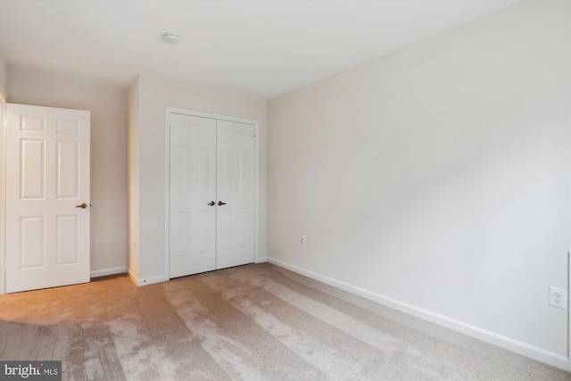 unfurnished bedroom with a closet and light carpet