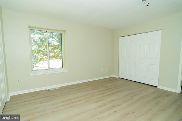 unfurnished bedroom featuring light hardwood / wood-style floors and a closet