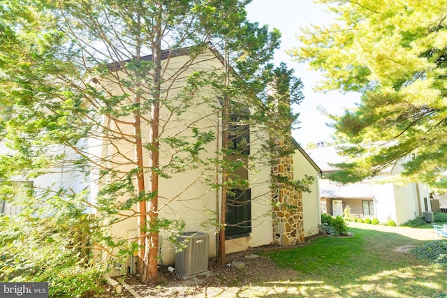 view of property exterior with a yard and central AC