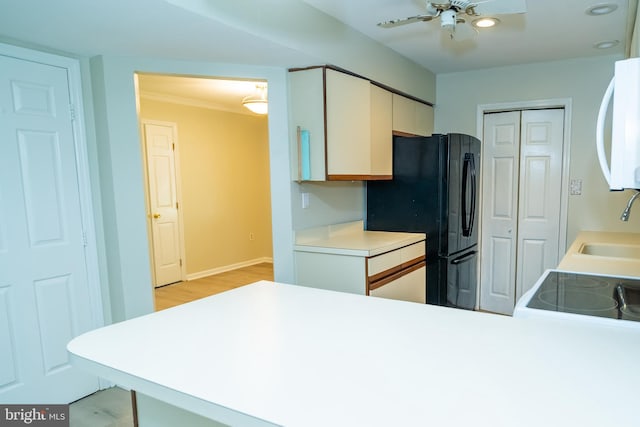 kitchen featuring black refrigerator, sink, kitchen peninsula, and ceiling fan