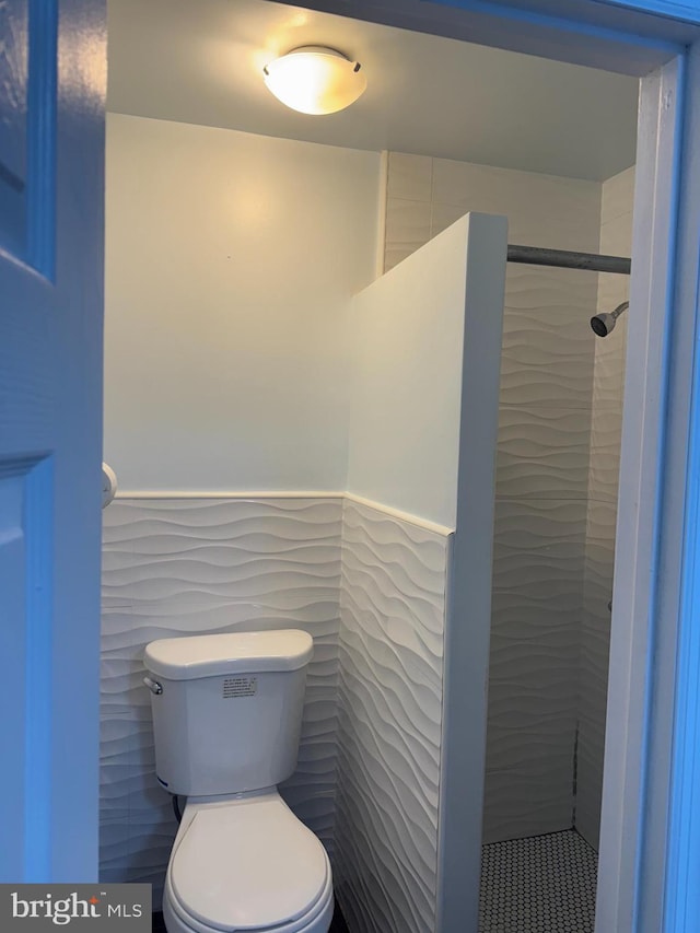 bathroom featuring tiled shower and toilet