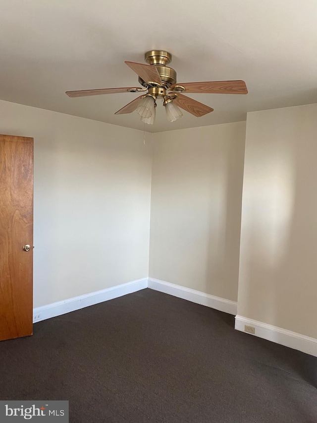 spare room featuring ceiling fan and dark carpet