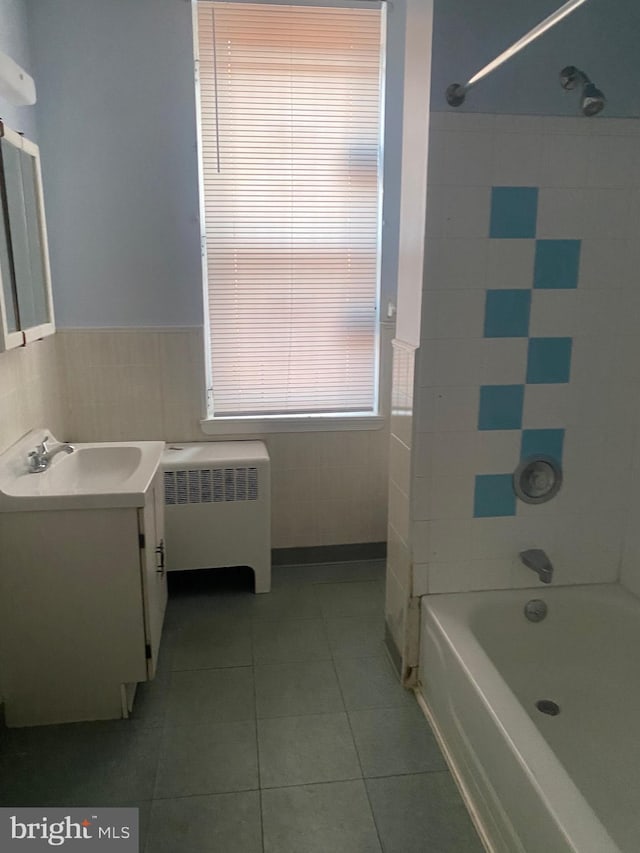 bathroom featuring tile walls, radiator heating unit, vanity, tile patterned floors, and tiled shower / bath