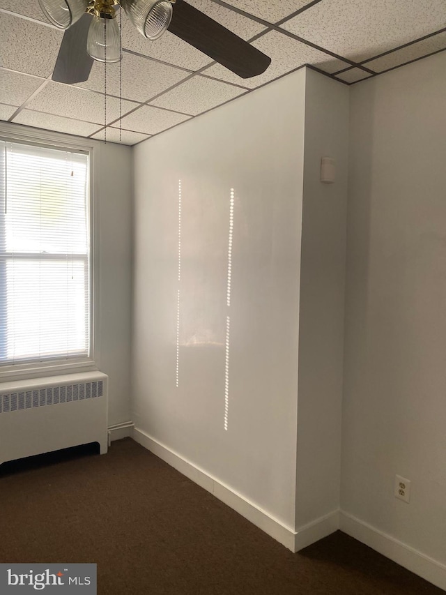 empty room with radiator, a paneled ceiling, and ceiling fan