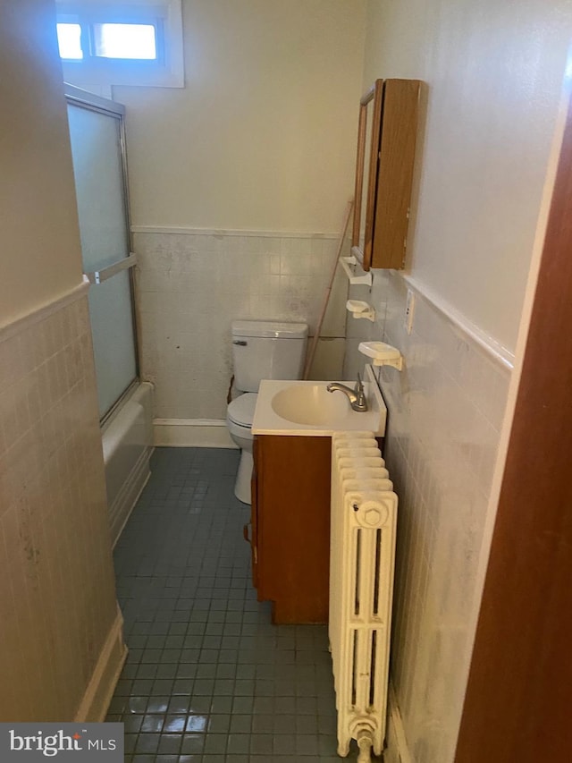 full bathroom with toilet, bath / shower combo with glass door, tile walls, radiator, and tile patterned flooring