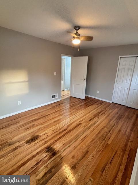 unfurnished bedroom featuring a textured ceiling, a closet, ceiling fan, and light wood-type flooring