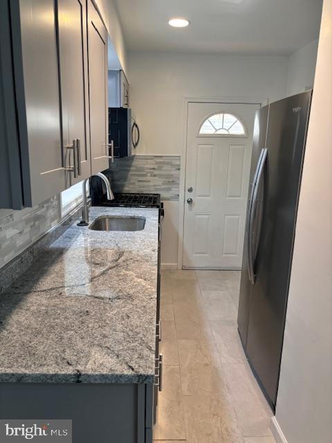 kitchen featuring stainless steel appliances, tasteful backsplash, sink, and dark stone countertops