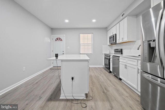 kitchen with stainless steel appliances, white cabinetry, a center island, and decorative backsplash