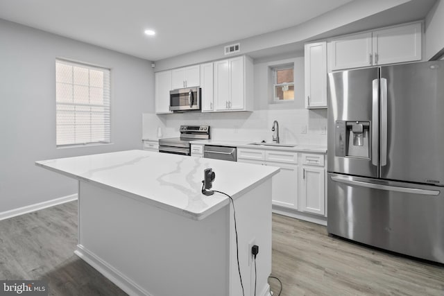 kitchen with light stone countertops, appliances with stainless steel finishes, sink, and white cabinets