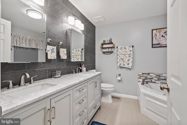 bathroom featuring tile walls, tasteful backsplash, vanity, a bath, and toilet